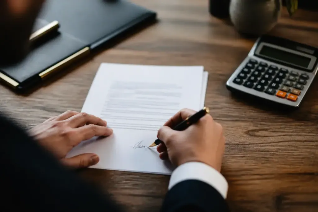 Bureau en bois avec contrat signe, stylo et calculatrice