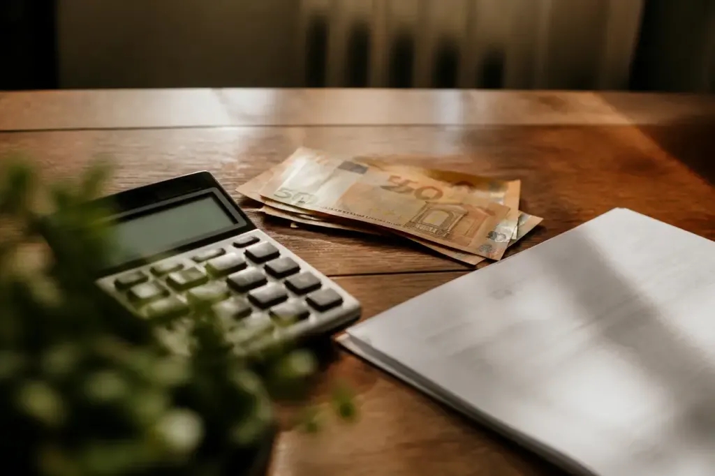 Calculatrice, billets et facture sur un bureau en bois