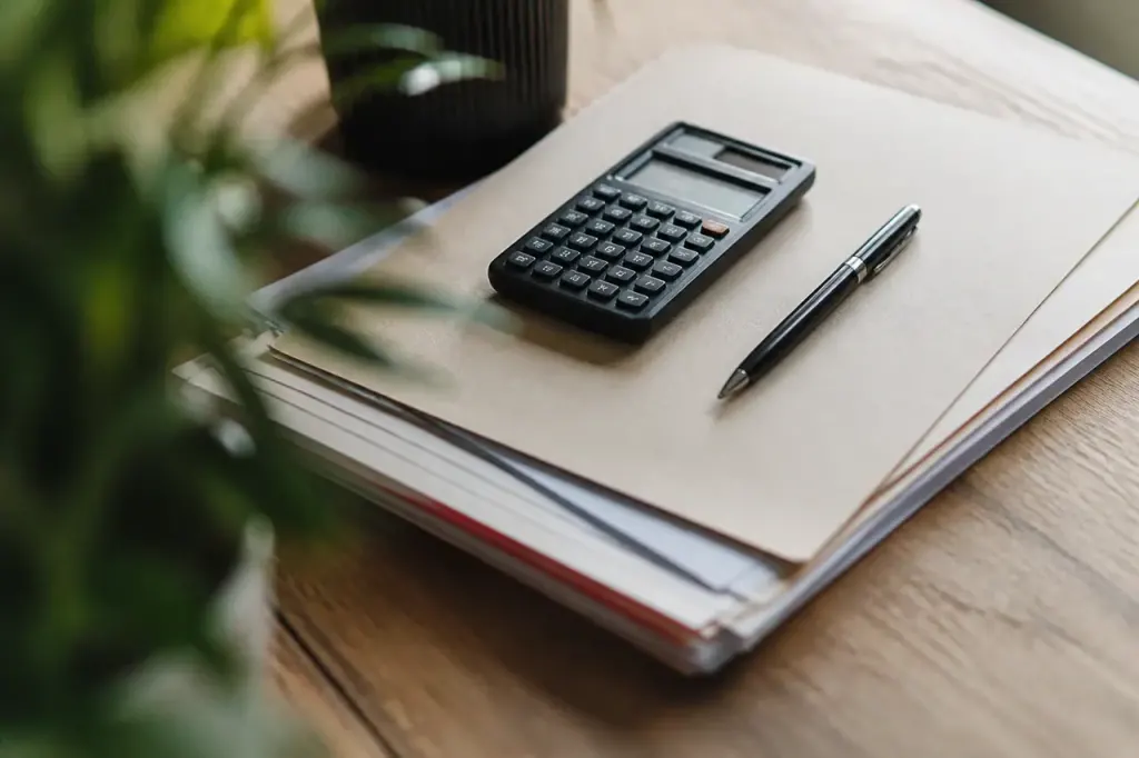 Calculatrice et stylo poses sur un dossier papier