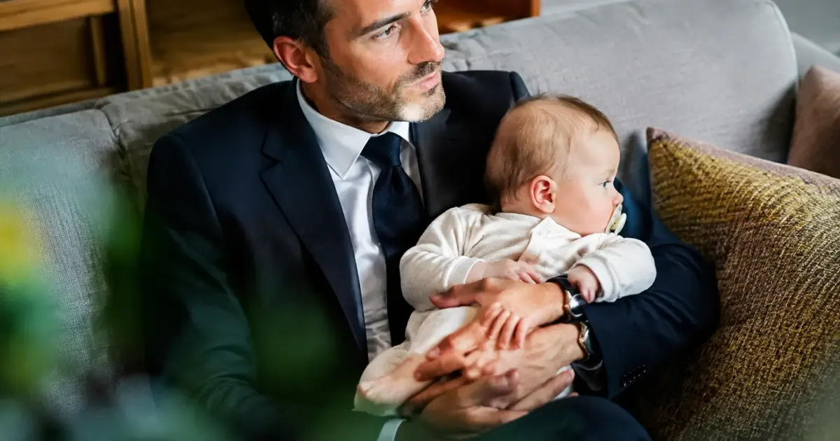 Chef d'entreprise assis sur un canape tenant un bebe