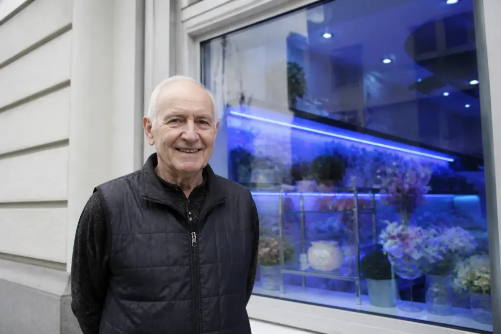 Commercant souriant devant une vitrine avec enseigne lumineuse bleue