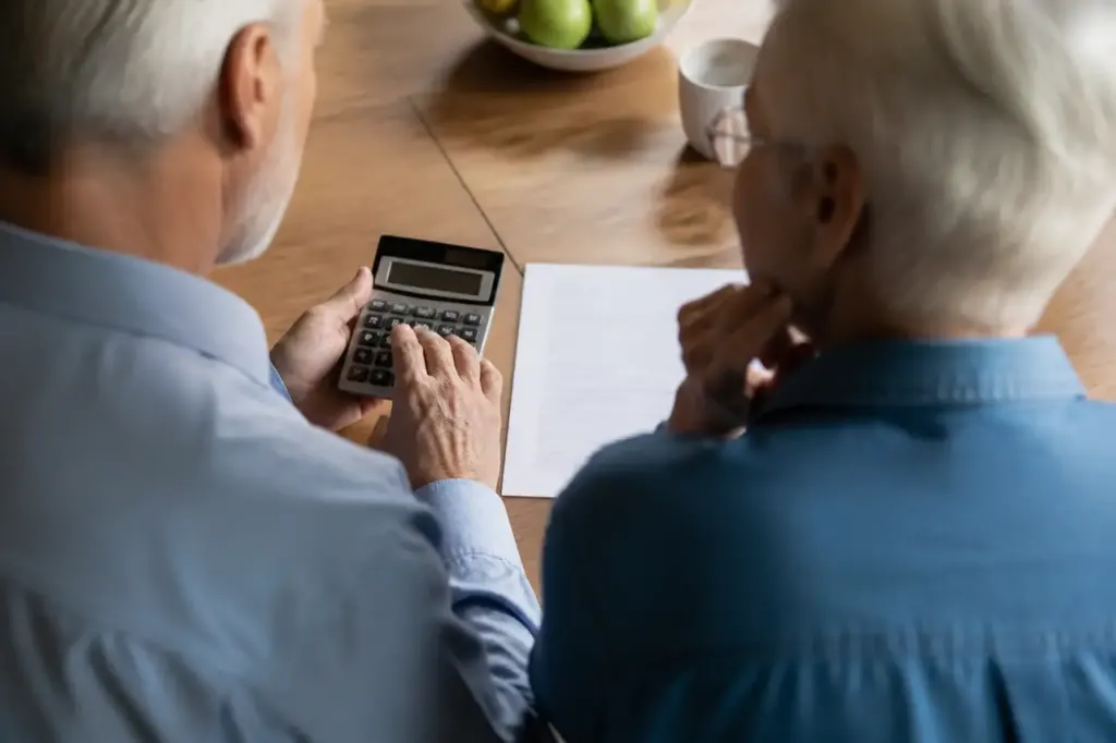 Couple senior avec calculatrice et bail sur table