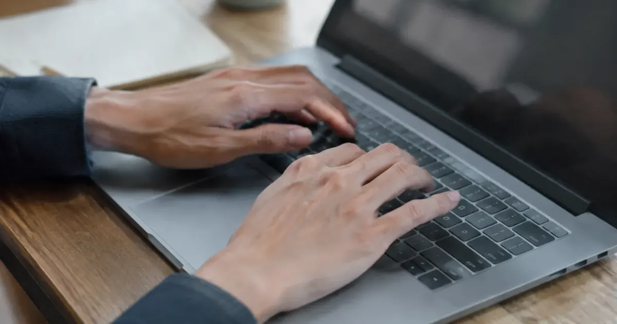 Deux mains posees sur un clavier portable gris