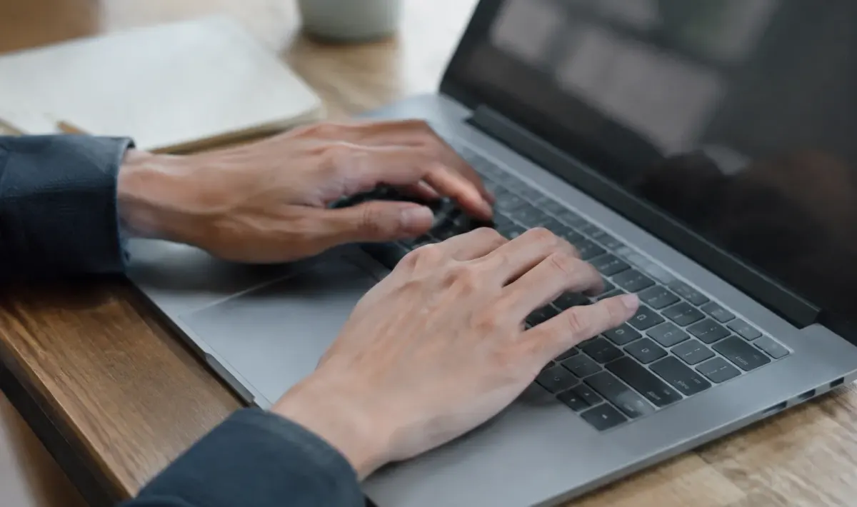 Deux mains posees sur un clavier portable gris