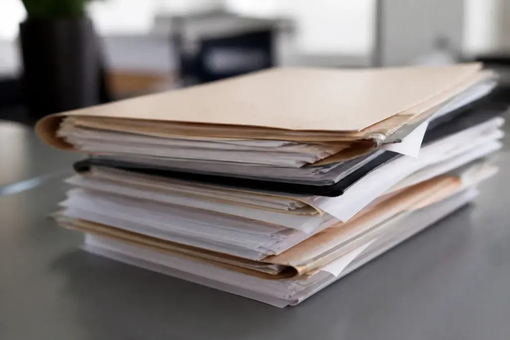 Dossiers commerciaux empiles sur bureau gris