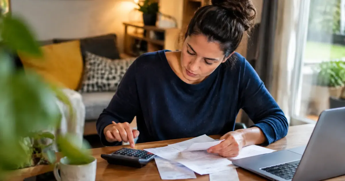 Femme assise, calculatrice et factures posées sur le bureau