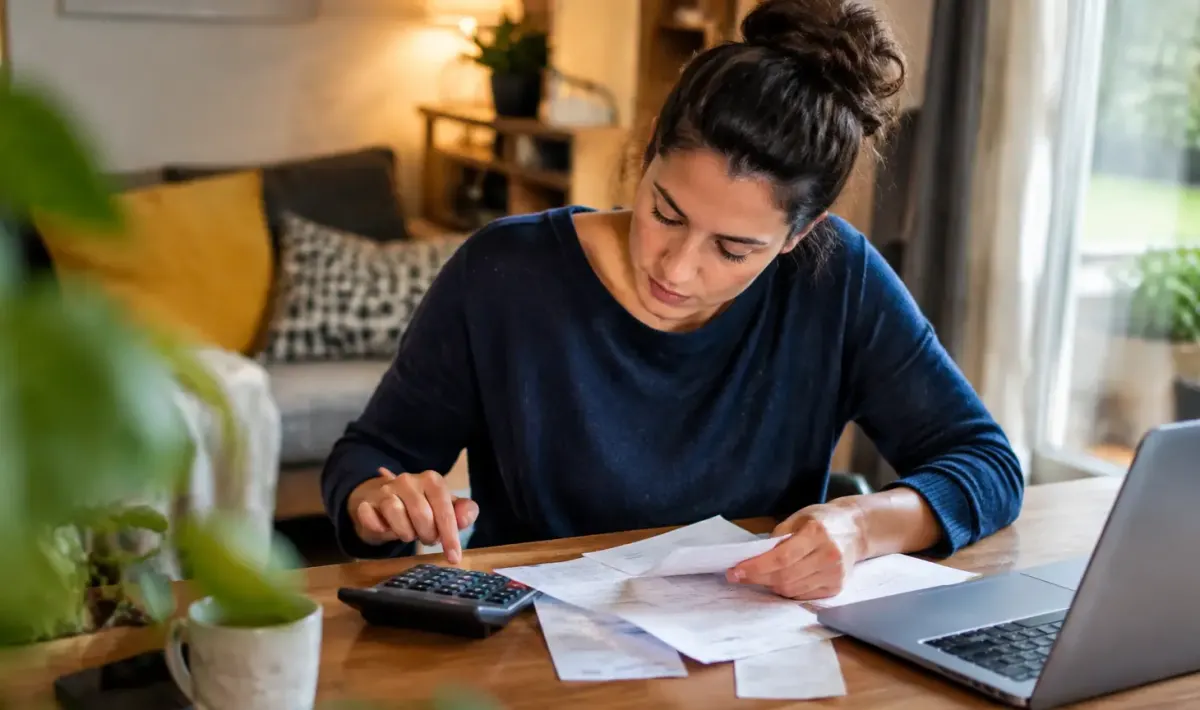 Femme assise, calculatrice et factures posées sur le bureau