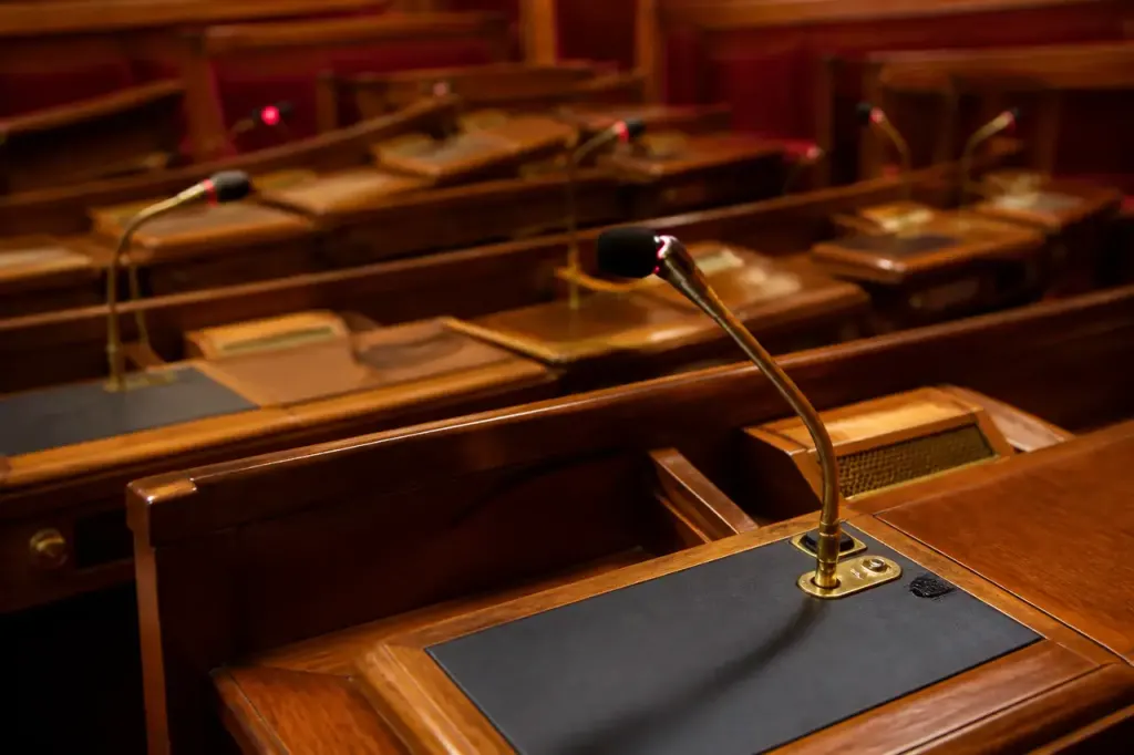 Hemicycle vide avec pupitres en bois et micros allumes