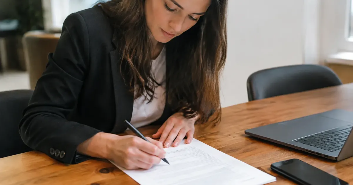 Main signant un contrat sur un bureau en bois
