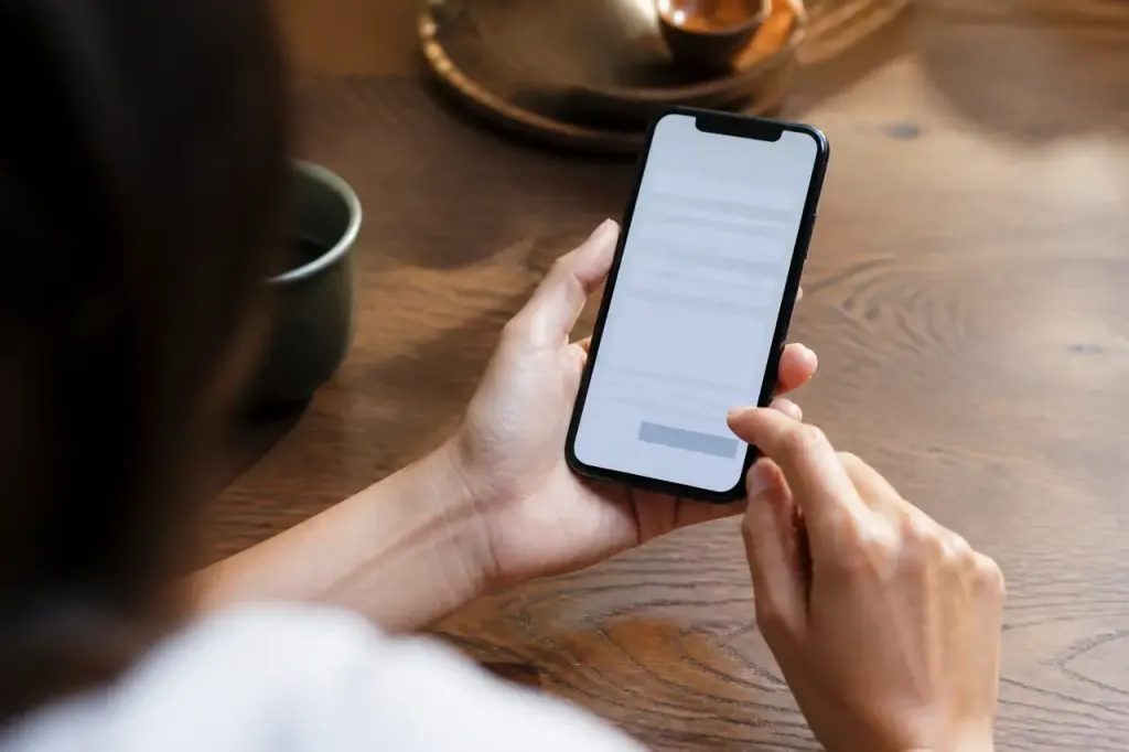 Main tenant un smartphone affichant un formulaire sur table