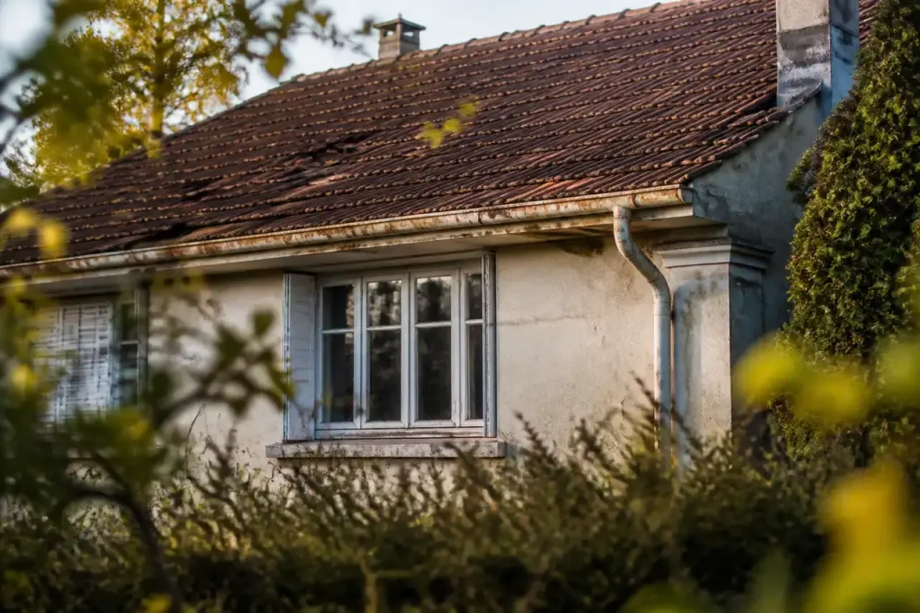 Maison individuelle avec toiture abimee et gouttieres rouillees