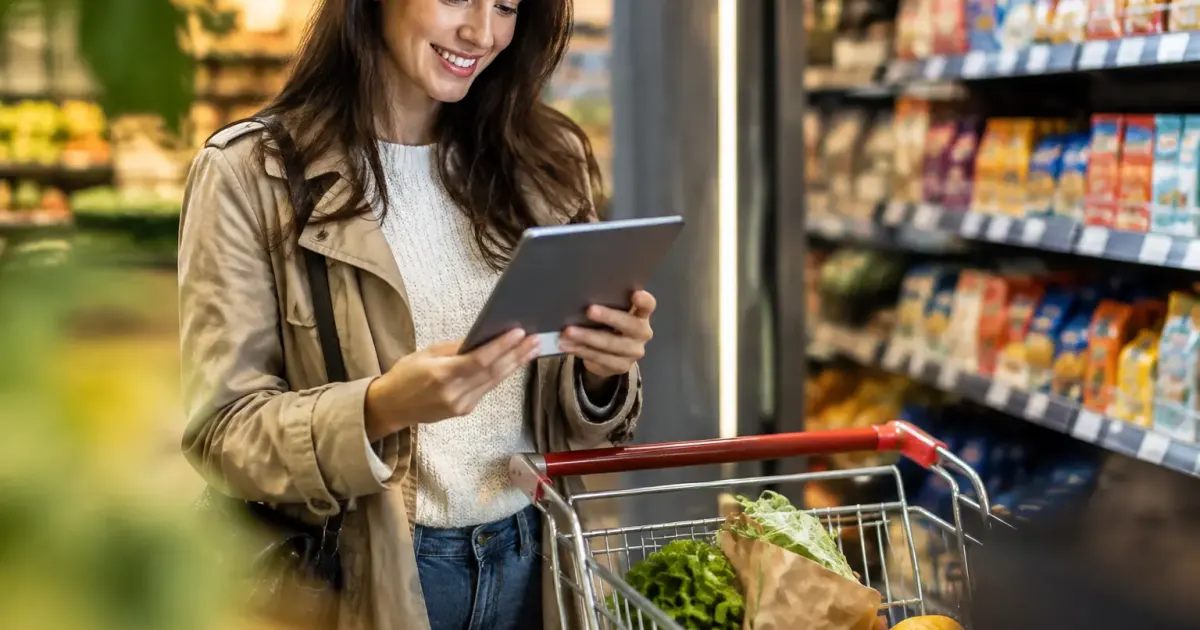 Mere souriante tenant une tablette pres du caddie