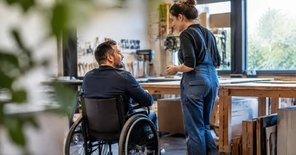 Patron et employe en fauteuil roulant devant un atelier