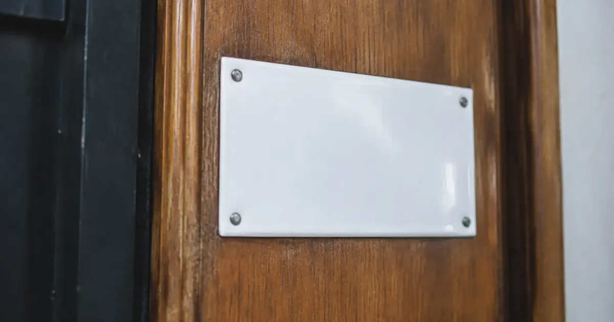 Plaque metallique emaillee blanche fixee sur porte bois