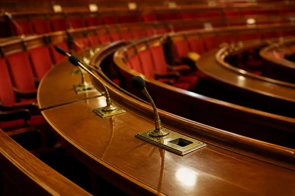 Pupitres en bois et micros dans un hemicycle vide